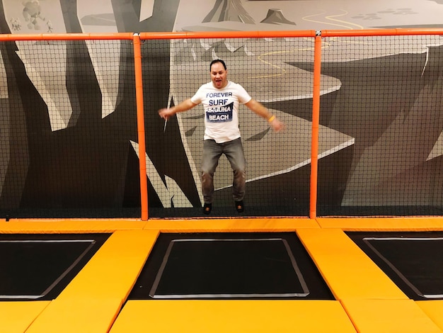 Foto hombre feliz saltando por encima del trampolín amarillo