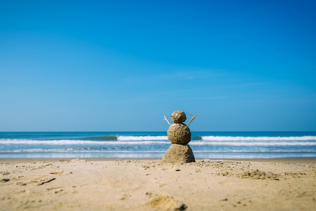 Hombre feliz de Sandy en la playa del mar contra el cielo nublado azul del verano - concepto del viaje.