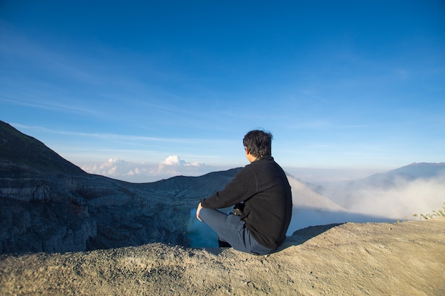 hombre feliz sentado en la parte superior Kawah ijen