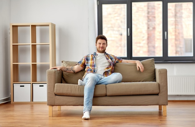 Foto hombre feliz sentado en el sofá en su nueva casa