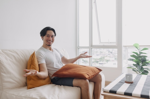 Hombre feliz se sienta y se relaja en el sofá de la sala de estar del apartamento