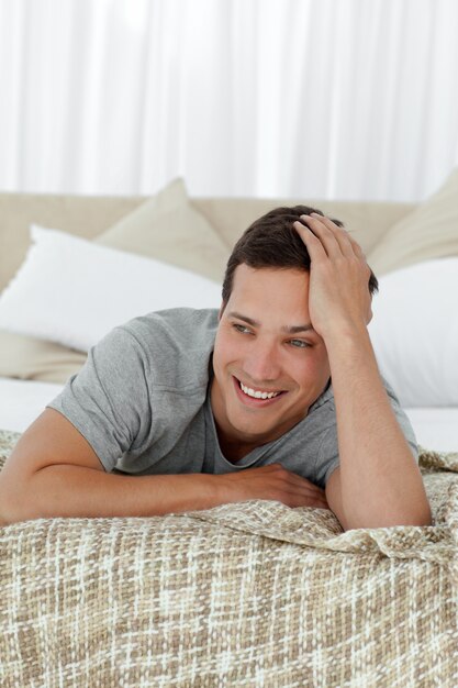 Hombre feliz sonriendo acostado en su cama