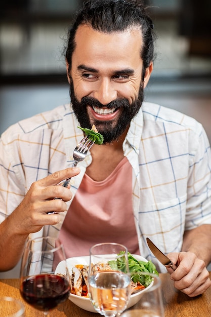 Un hombre feliz y sonriente comiendo en un restaurante.