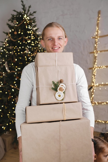 Hombre feliz sosteniendo la cama pila de regalos de Navidad