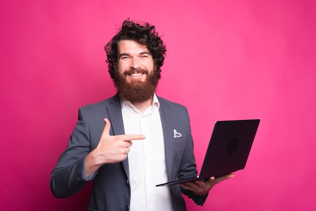 Hombre feliz sosteniendo una computadora y sonriendo a la cámara