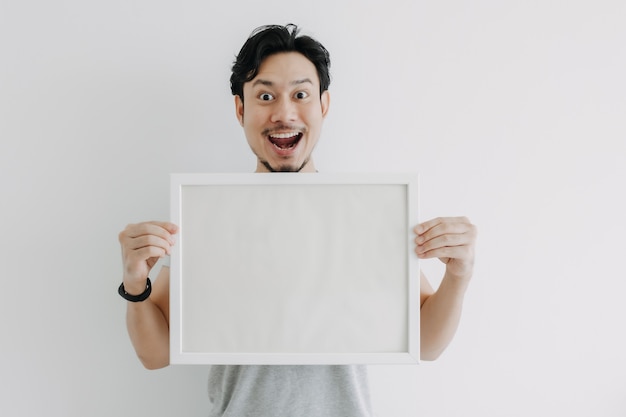 Hombre feliz sosteniendo un marco de fotos vacío aislado sobre fondo blanco.