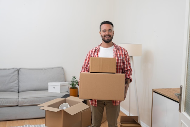 Un hombre feliz sostiene cajas de envío empaquetadas en un apartamento renovado