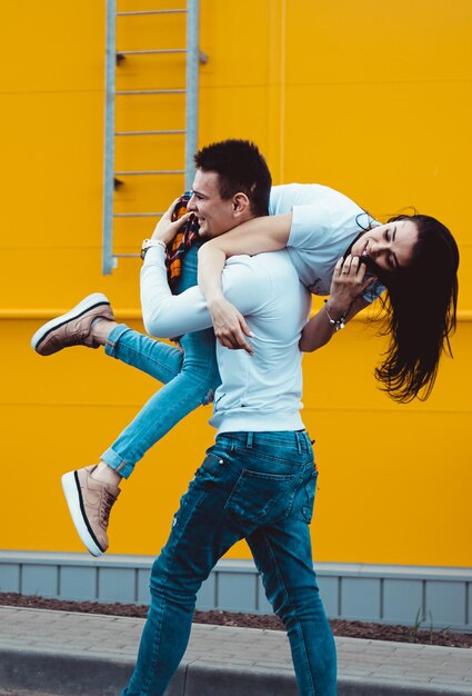 Hombre feliz con su novia sobre fondo amarillo - pareja de enamorados