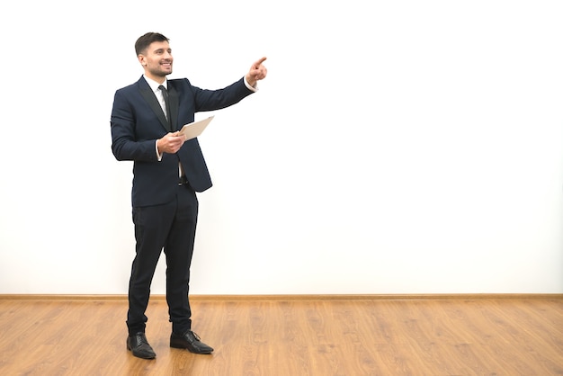 El hombre feliz con una tableta haciendo un gesto sobre el fondo de la pared blanca