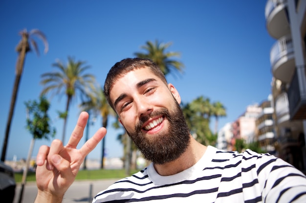 Hombre feliz tomando selfie por palmeras