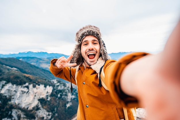 Hombre feliz tomando un selfie subiendo montañas