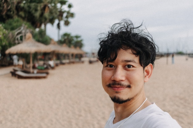 Hombre feliz tomar selfie con palmera en el concepto de viajes de verano de playa