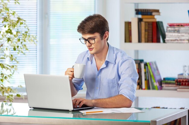 Foto hombre feliz trabajando en la computadora portátil en la biblioteca