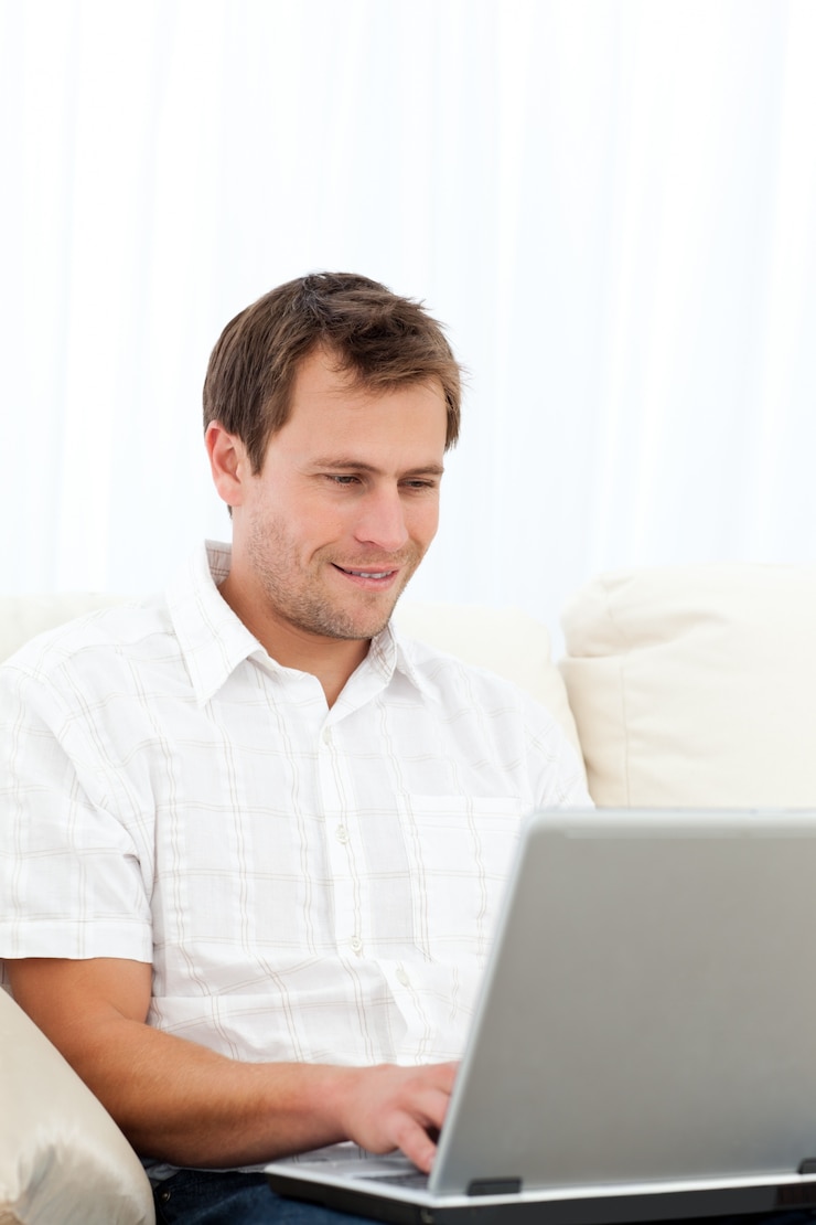 Foto hombre feliz trabajando en su computadora portátil en el sofá