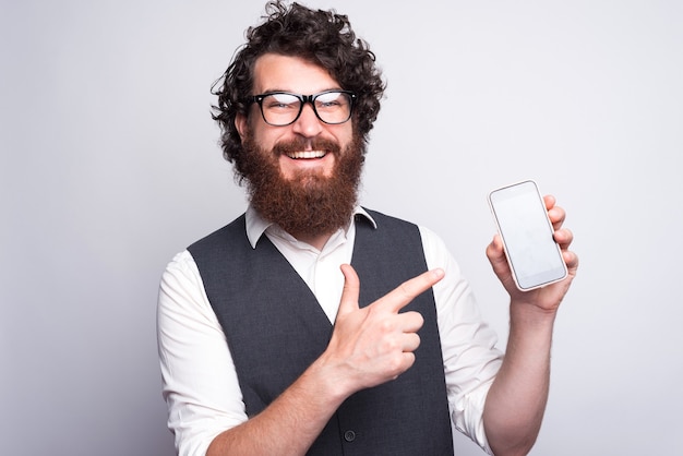 hombre feliz en traje apuntando a la pantalla del teléfono inteligente.