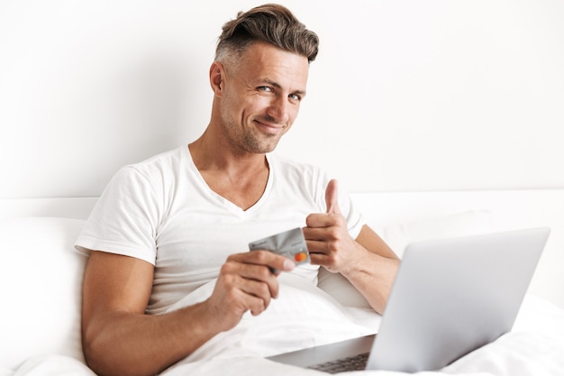 Foto hombre feliz usando la computadora portátil y mostrando los pulgares para arriba