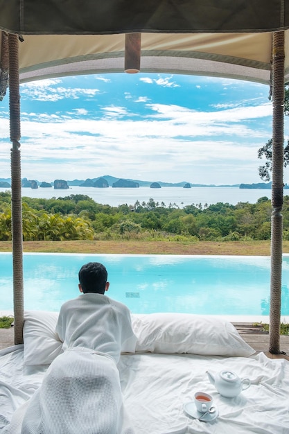 Hombre feliz viajero disfrutar Hermosa vista al mar Turista relajante en un resort de lujo tropical con piscina Viajes de ocio y concepto de vacaciones de verano