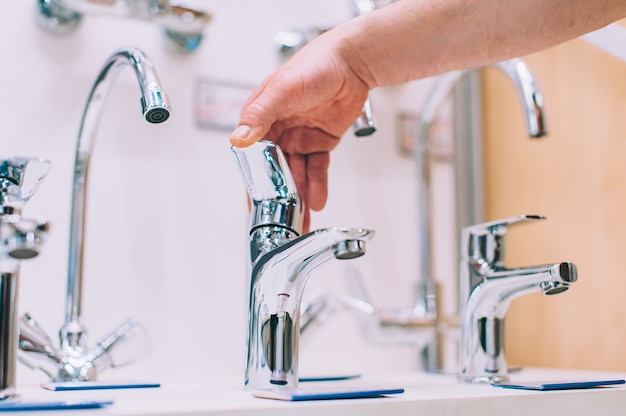 Un hombre en una ferretería selecciona un grifo para el fregadero y el lavabo.