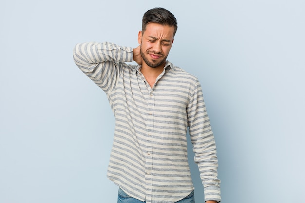 Hombre filipino guapo joven que sufre dolor de cuello debido al estilo de vida sedentario.