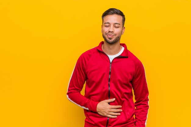 El hombre filipino joven de la aptitud toca la panza, sonríe suavemente, comiendo y concepto de la satisfacción.