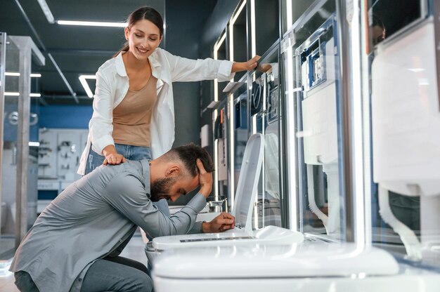 Hombre fingiendo que se siente mal en el baño Mujer y hombre están en la tienda de artículos para el hogar