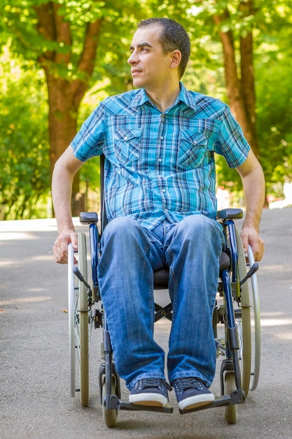 Foto hombre físicamente discapacitado mirando hacia otro lado mientras está sentado en silla de ruedas