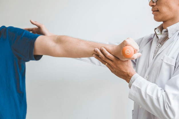 Hombre fisioterapeuta haciendo ejercicio con tratamiento con mancuernas Acerca del brazo y el hombro