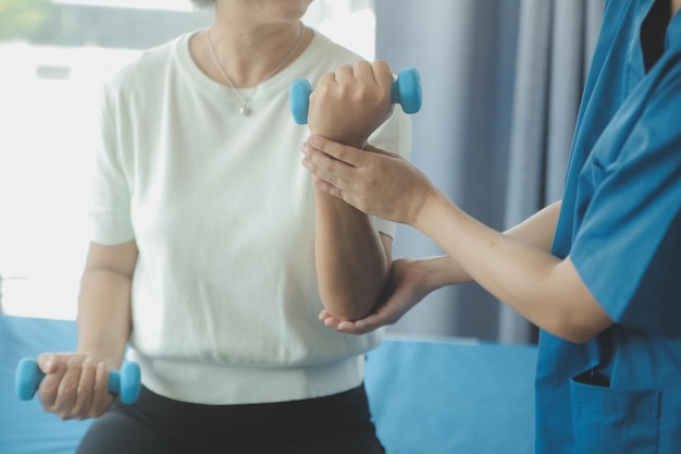 Hombre de fisioterapeuta que da ejercicio con tratamiento con mancuernas Acerca del brazo y el hombro del atleta Hombre paciente Concepto de terapia física