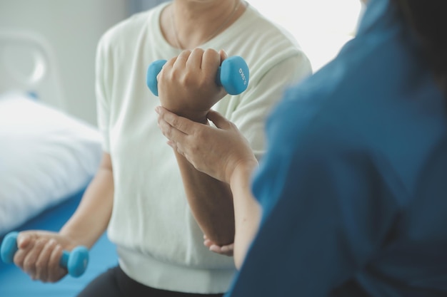 Hombre de fisioterapeuta que da ejercicio con tratamiento con mancuernas Acerca del brazo y el hombro del atleta Hombre paciente Concepto de terapia física