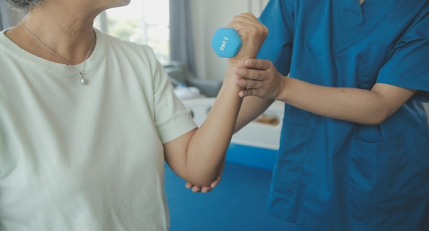 Hombre de fisioterapeuta que da ejercicio con tratamiento con mancuernas Acerca del brazo y el hombro del atleta Hombre paciente Concepto de terapia física