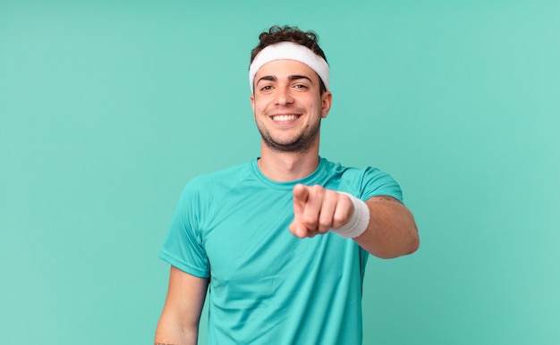 Hombre de fitness apuntando a la cámara con una sonrisa satisfecha, confiada y amistosa, eligiéndote