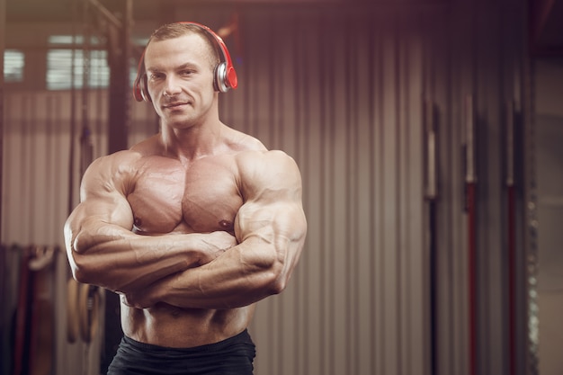 Hombre fitness con auriculares en entrenamiento en gimnasio