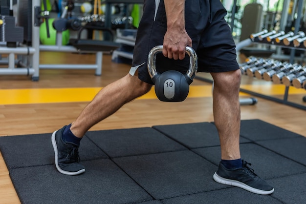 Hombre de fitness ejercicio con pesas rusas en el gimnasio moderno.