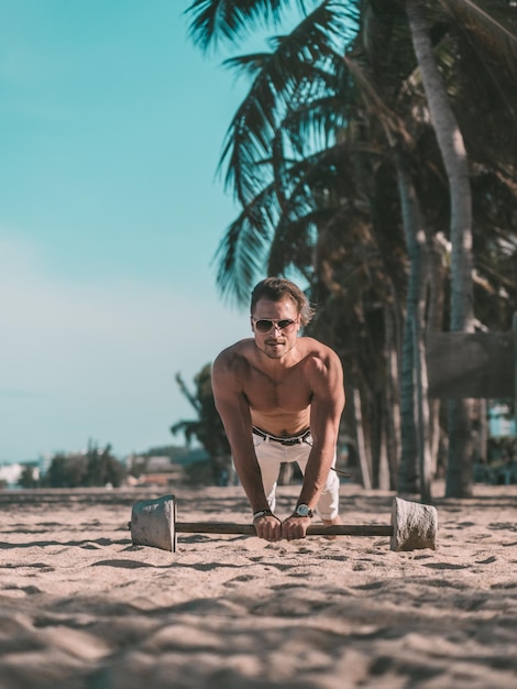 Foto hombre fitness haciendo flexiones en la playa