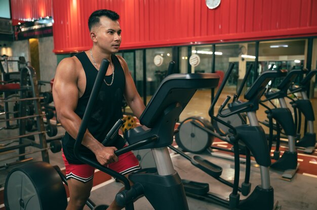 Hombre fitness con máquina de entrenamiento en el gimnasio