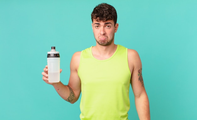 Hombre de fitness que se siente triste y quejumbroso con una mirada infeliz, llorando con una actitud negativa y frustrada