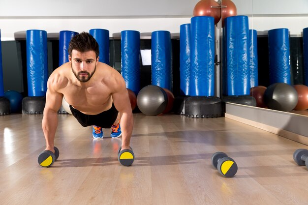 Hombre de flexiones de pesas en el gimnasio