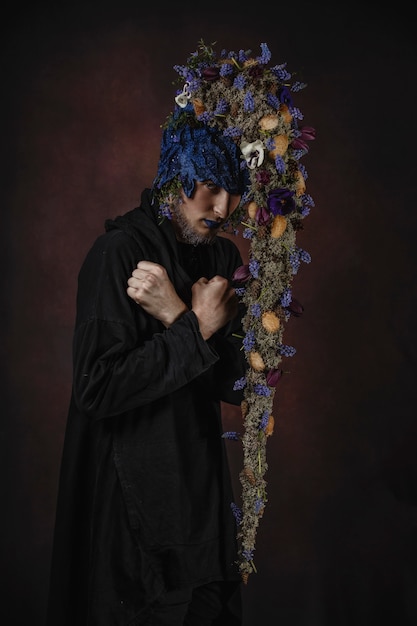 Un hombre con flores azules en un cuarto oscuro