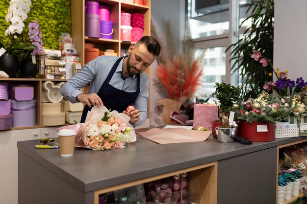 Hombre florista en el trabajo recoge ramos de rosas como regalo para el día de san valentín