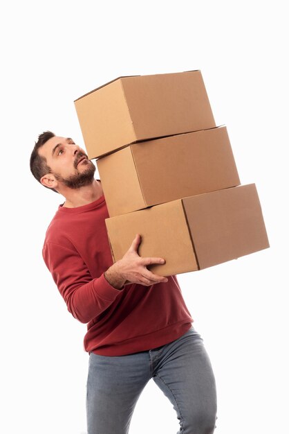 Foto hombre con fondo blanco sosteniendo cajas y tratando de no dejarlas caer ayuda para la entrega a domicilio