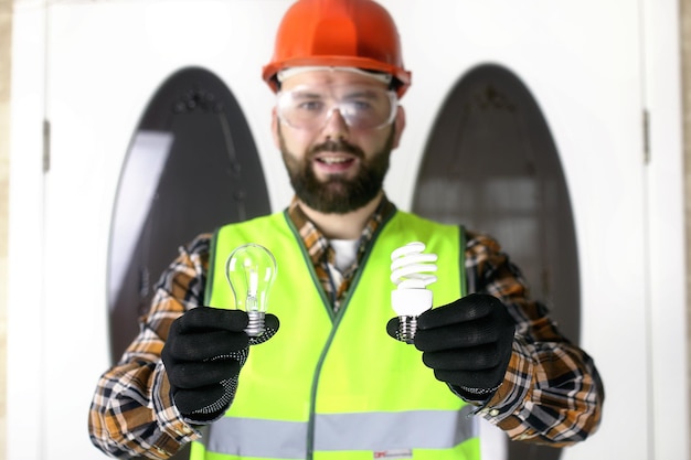 El hombre en forma de casco y guantes, sosteniendo una bombilla