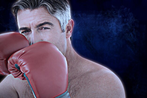 Foto hombre en forma golpeando con guantes de boxeo contra un fondo oscuro