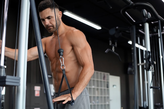 Hombre en forma y musculoso entrena los músculos pectorales en un simulador de bloques en el gimnasio.