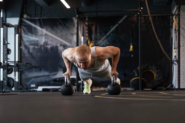 Hombre en forma y musculoso haciendo flexiones horizontales con barras en el gimnasio