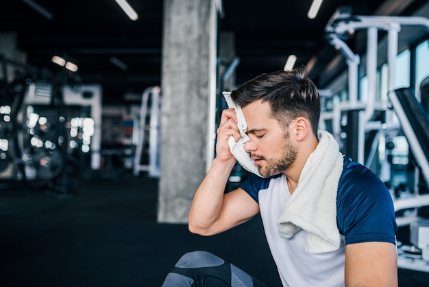 Hombre en forma tomando un descanso de hacer ejercicio en el gimnasio.