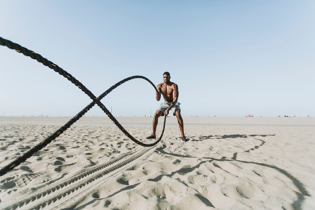 Hombre en forma trabajando con cuerdas de batalla