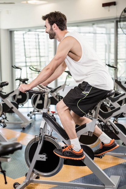 Hombre en forma usando bicicleta en el gimnasio