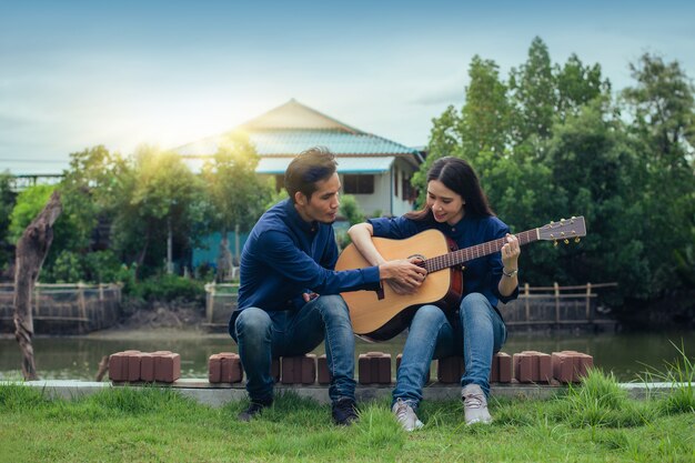 Hombre formación guitarra con mujer sentada en el parque naturaleza descanso vacaciones de verano