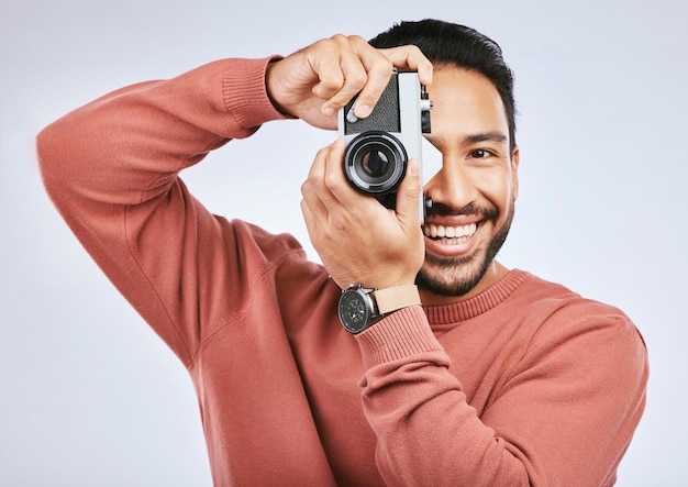 Hombre con fotografía de cámara y sonrisa en retrato con creatividad y arte aislado en el fondo del estudio Fotógrafo masculino feliz creativo con persona artística y tomando fotos con gadget