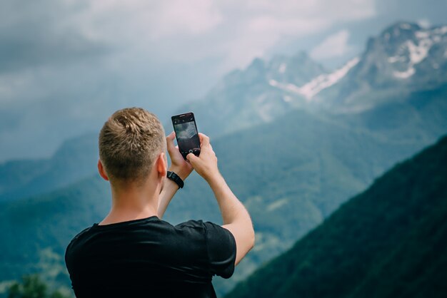 El hombre fotografía la cámara del teléfono inteligente montañas